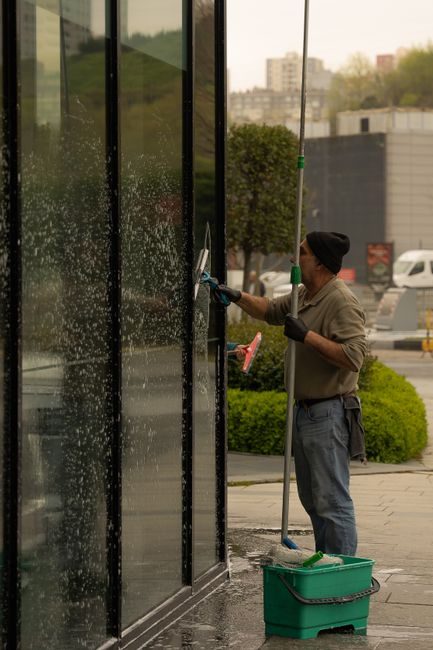 Laveur de vitres à la raclette sur une façade vitrée de bâtiment professionnel