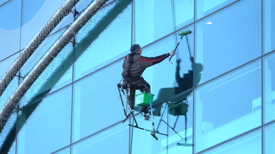 Laveur de vitres sur la façade vitrée d'un immeuble de bureaux